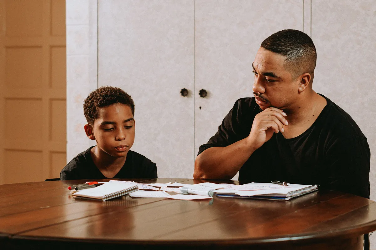 A parent and child working through homework at the table