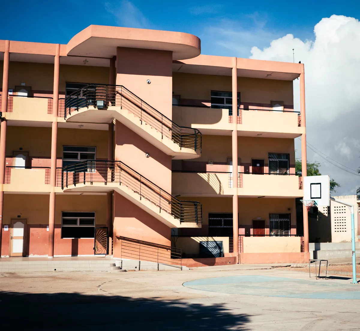 A three storey school building with open walkways and a basketball court