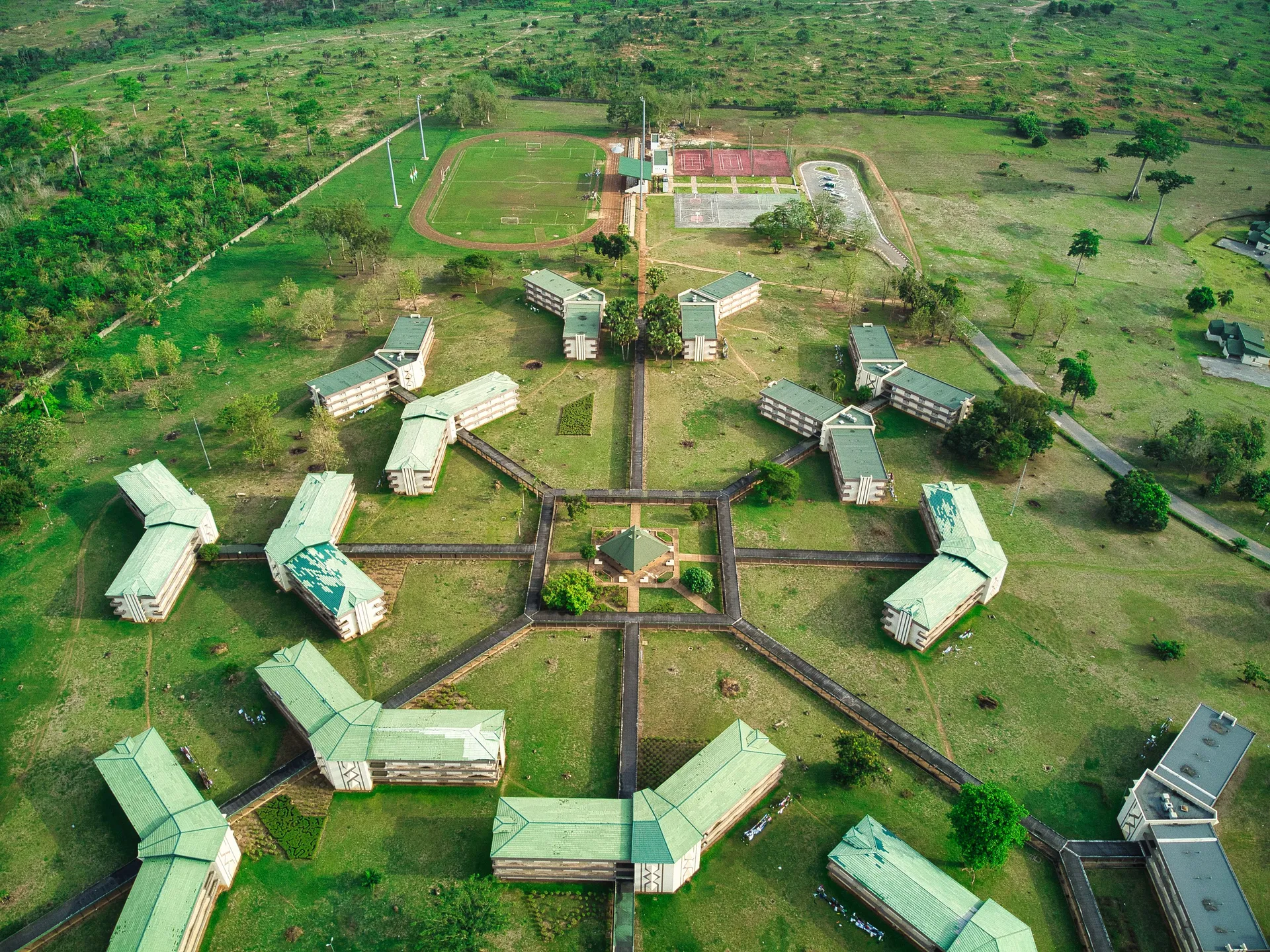 An aerial view of a school campus with green roofs and a sports field